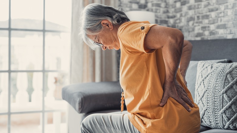 A senior holding her back in pain