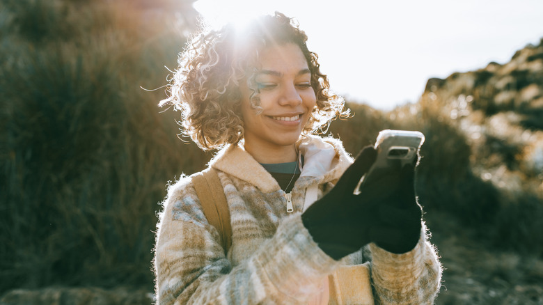 Woman using smartphone wearing gloves