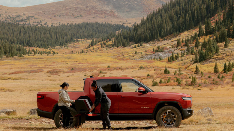 Rivian in the outdoors two people open the gear tunnel