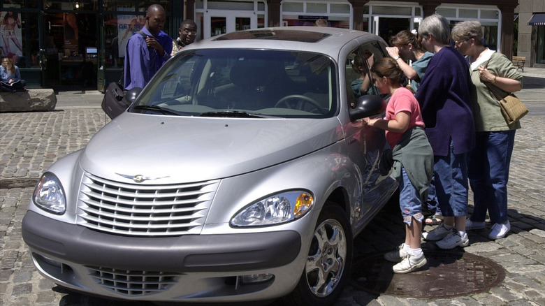 Bystanders gathering around a single Chrysler PT Cruiser