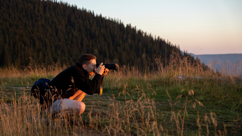 Crouched photographer in field