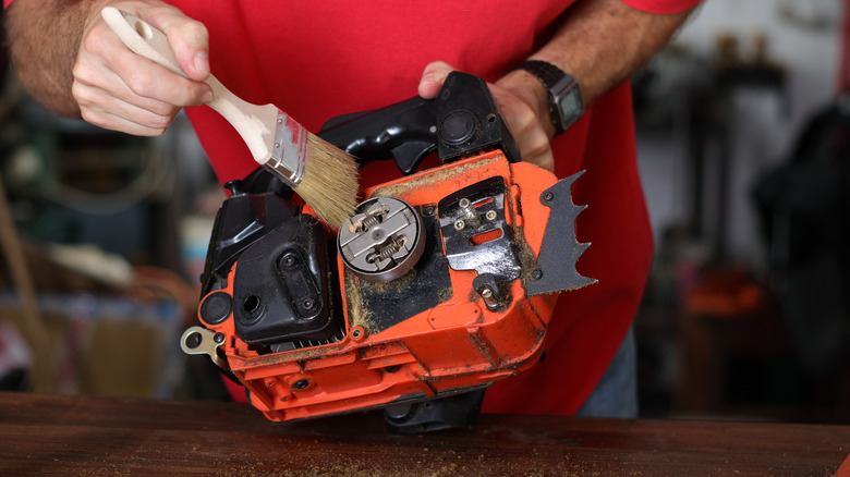 A Man Cleaning A Dismantled Chainsaw