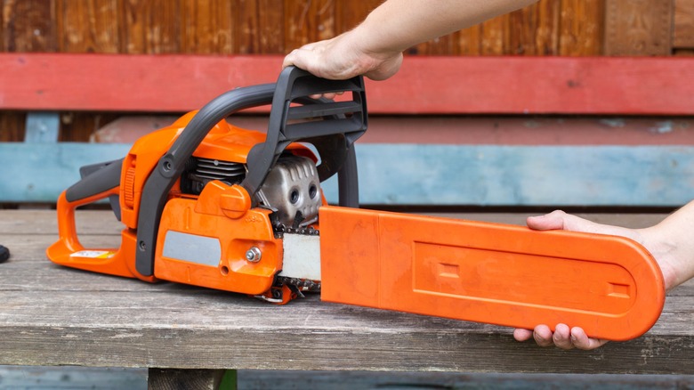 A Man Installing A Protective Sheath Over A Chainsaw