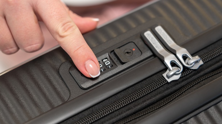 A woman trying different combinations on a suitcase lock.