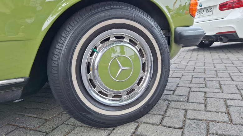 A vintage mercedes wheel with a green hubcap