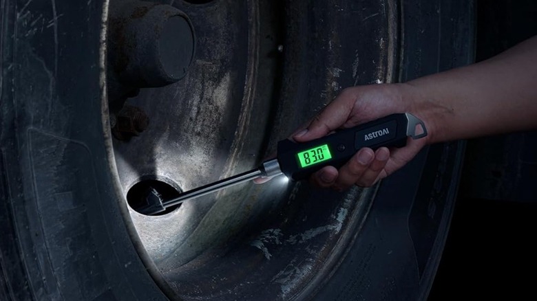 Person using tire pressure gauge