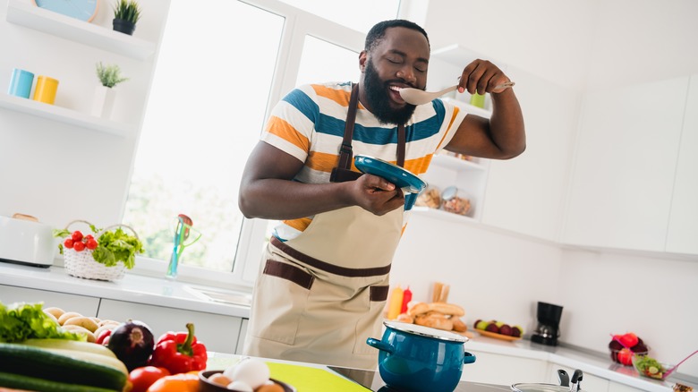 man tasting food in a kitchen