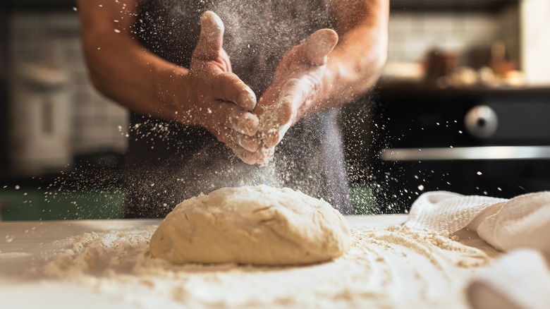 man dusting flour on dough