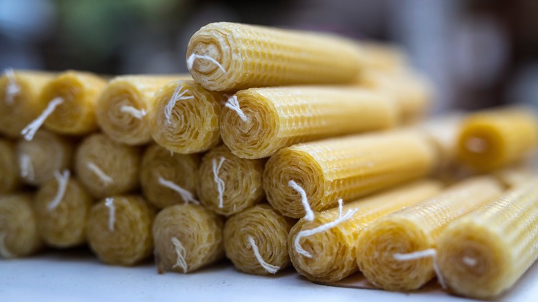 close-up pile of beeswax taper candles