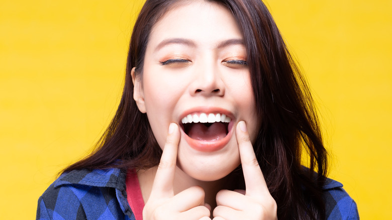 Woman smiling and pointing at teeth