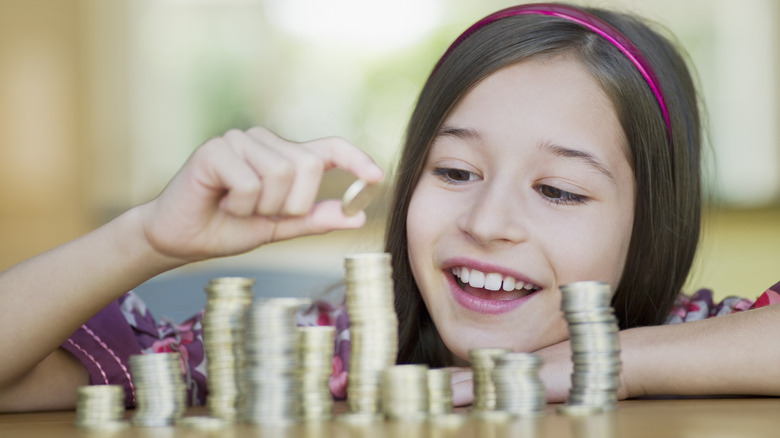 little girl counting coin stacks
