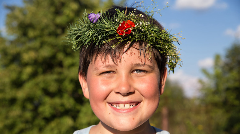 smiling boy with rosy cheeks wearing a flower crown