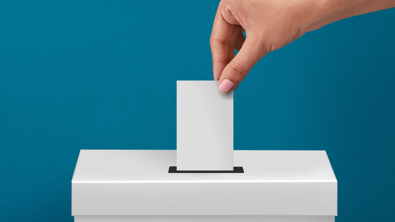 person dropping ballot into a box