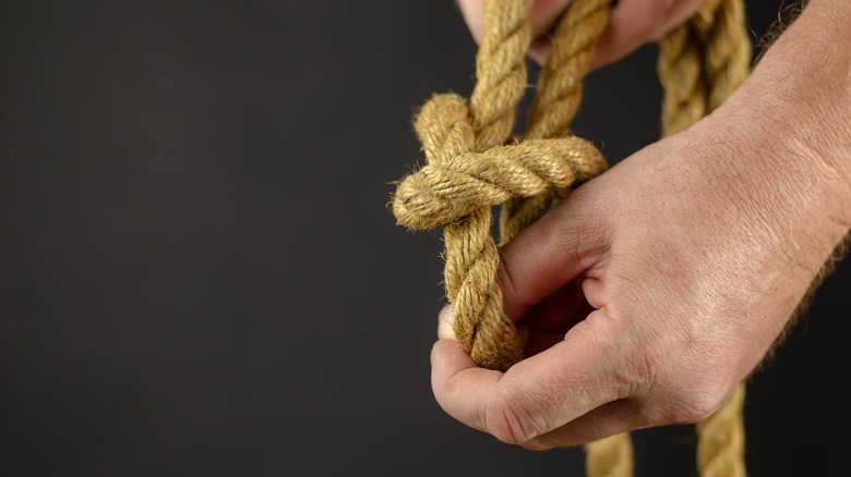 hands untying a rope knot