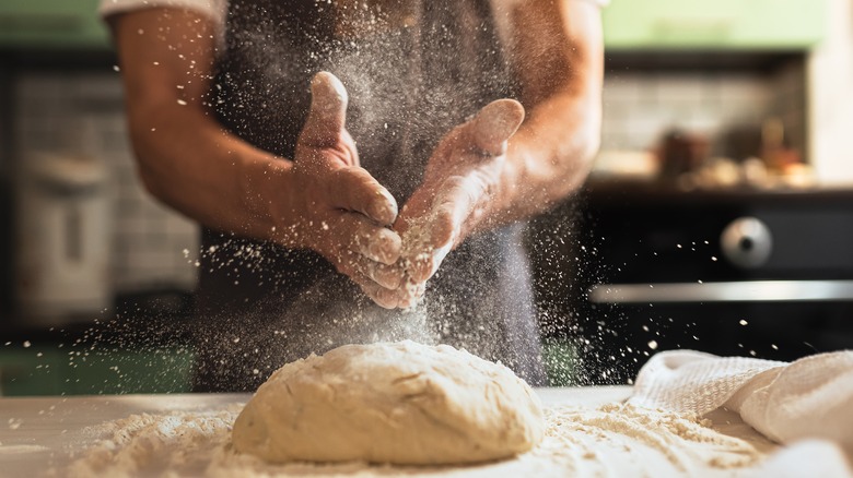 male chef dusting flour dough