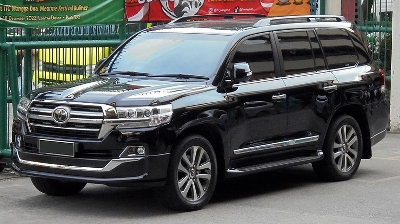 Black 2020 Toyota Land Cruiser VX-R parked by a green fence