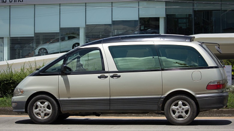 A silver Toyota Previa parked on the street in front of a building