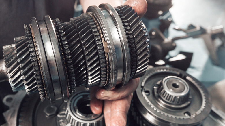 Dismantled vehicle transmission being held by mechanic