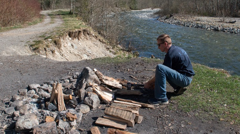 Man building fire at off-grid camping site