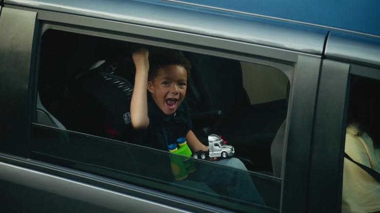 A kid in the backseat giving the trucker salute