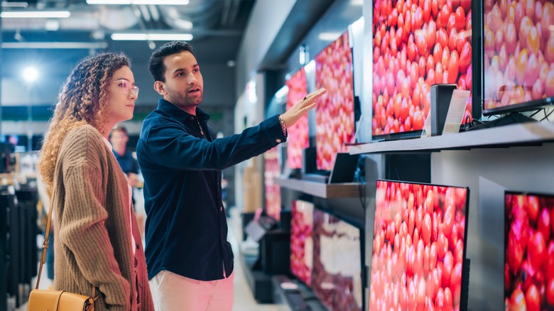 Two people looking at TVs