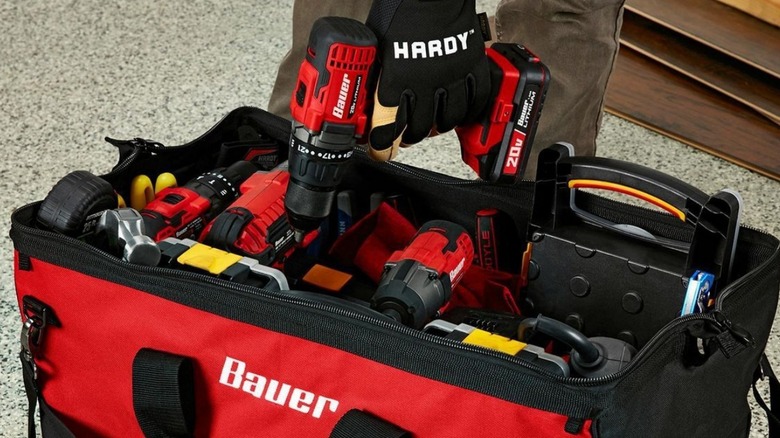 A person grabbing a Bauer drill/driver from their bauer tool bag