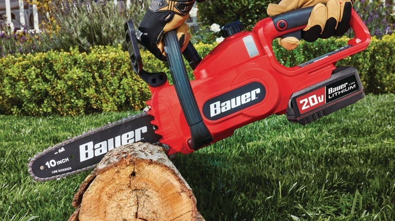 A person using a Bauer chainsaw to cut a log