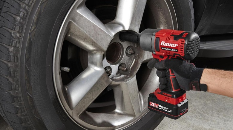 A person using a Bauer 1/2-drive impact wrench to remove a tire's lug nuts