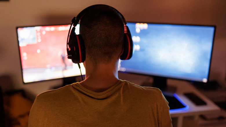 A man is playing a game on two monitors