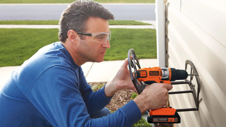 Person using drill on hose organizer