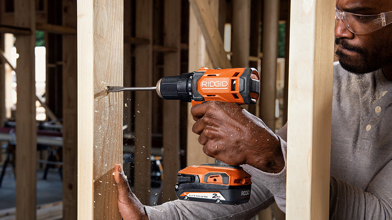 Person boring through lumber with drill