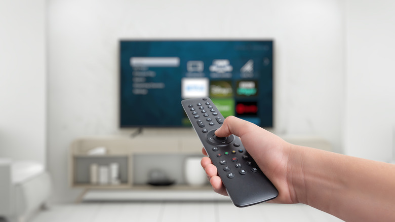 hand holding remote with out of focus TV behind