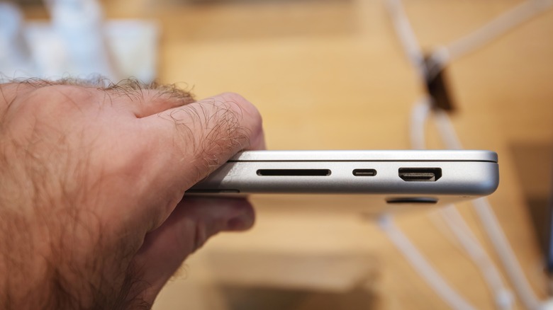 person holding MacBook Pro with SD card slot