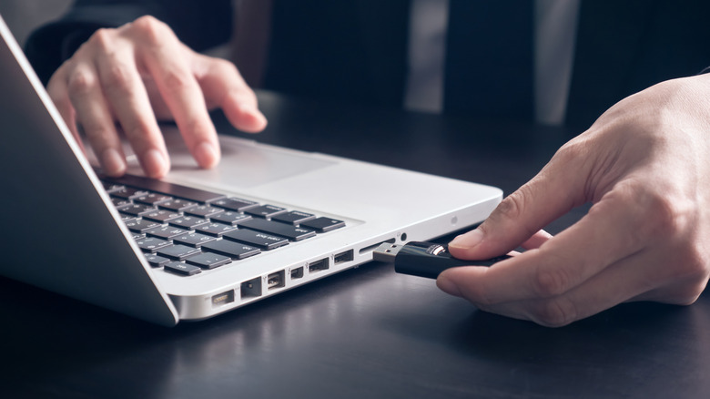 Closeup of a man inserting USB flash drive on laptop