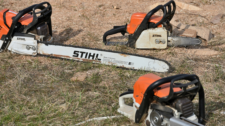 three Stihl chainsaws laying on the ground