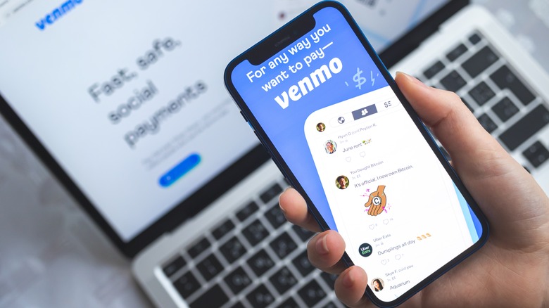 Hand holding phone with Venmo App displaying