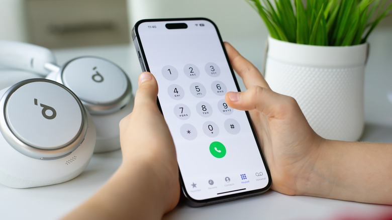 A person's hands holding iPhone with dialer open