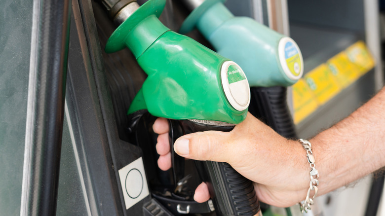 A hand holding a gas pump nozzle