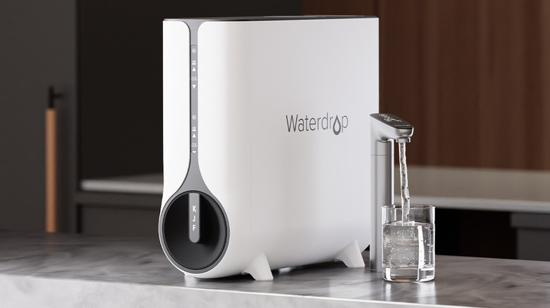 Waterdrop Filter sitting on counter as tap water pours into glass