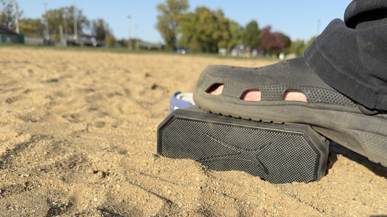 One speaker in the sand being stepped on