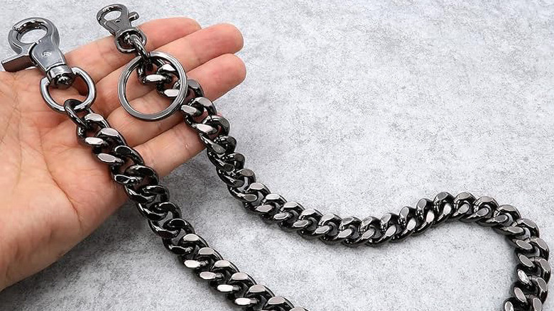 Black biker wallet chain held in fingers above gray and white surface