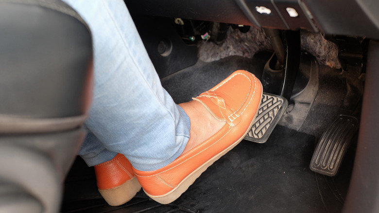 Person with shoes on car pedals