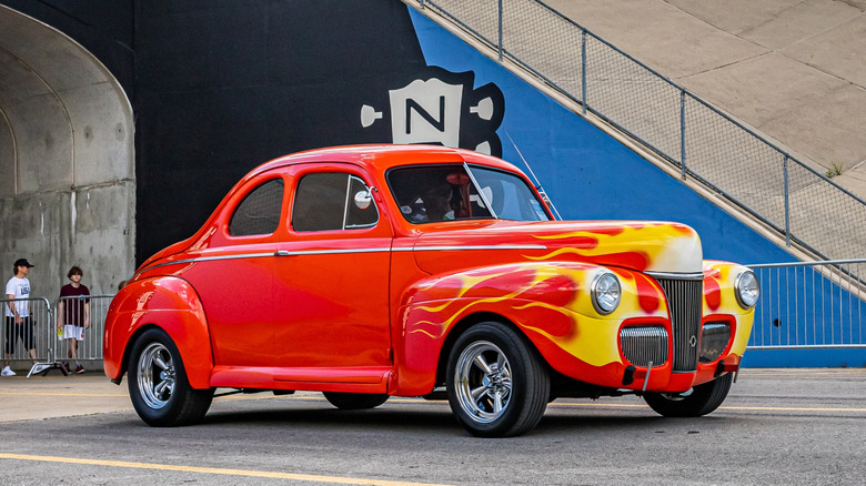 red Ford Deluxe Coupe hot rod driving on road