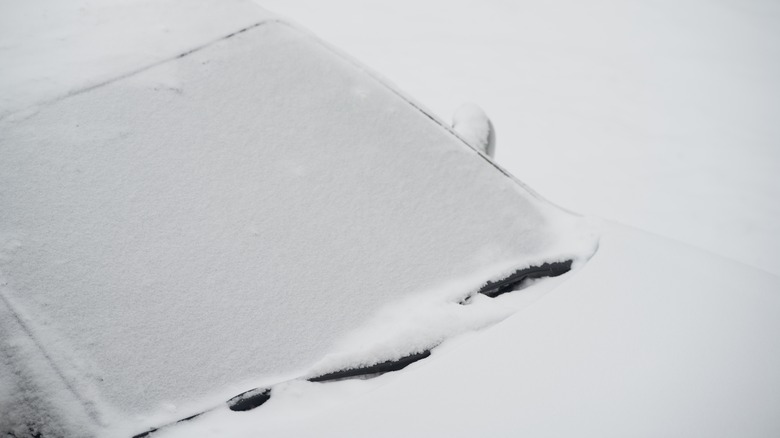 A snow-covered car with frozen wipers