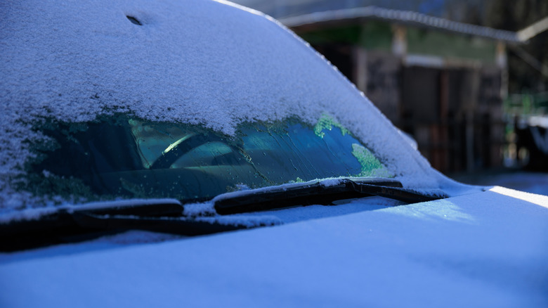 A heated windshield wiper bed melts snow on a car