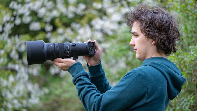 The Sigma FPL with the Sigma 500mm f/5.6 held by a man in front of out of focus flowers.