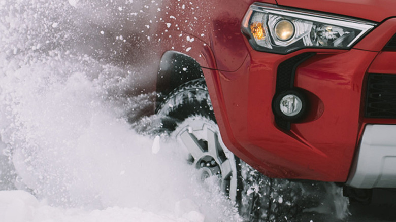 A red vehicle plows through heavy snow