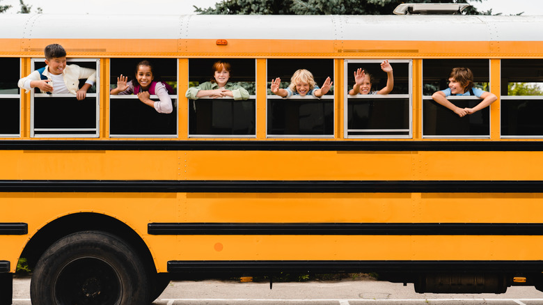 Side of a school bus with kids looking out the window