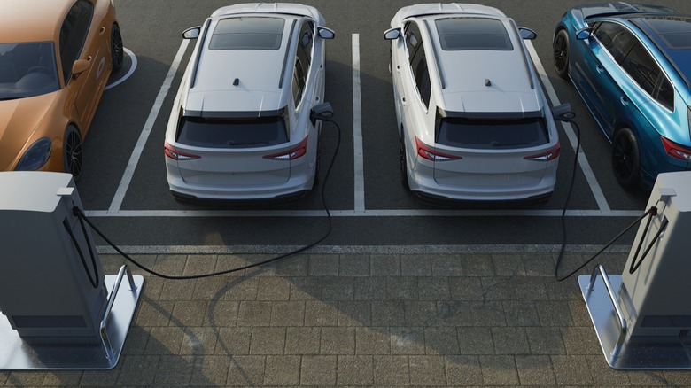 An aerial shot of an EV charging station with cars attached to chargers by long cords.