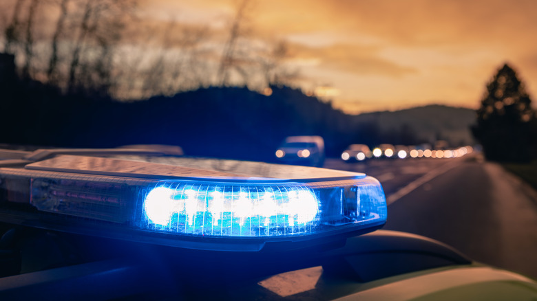 blue police light with road in the background at sunset.